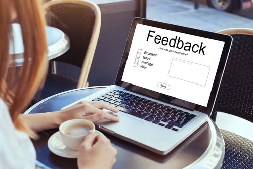 Close-Up of a woman drinking coffee and using a laptop with a feedback form on the screen