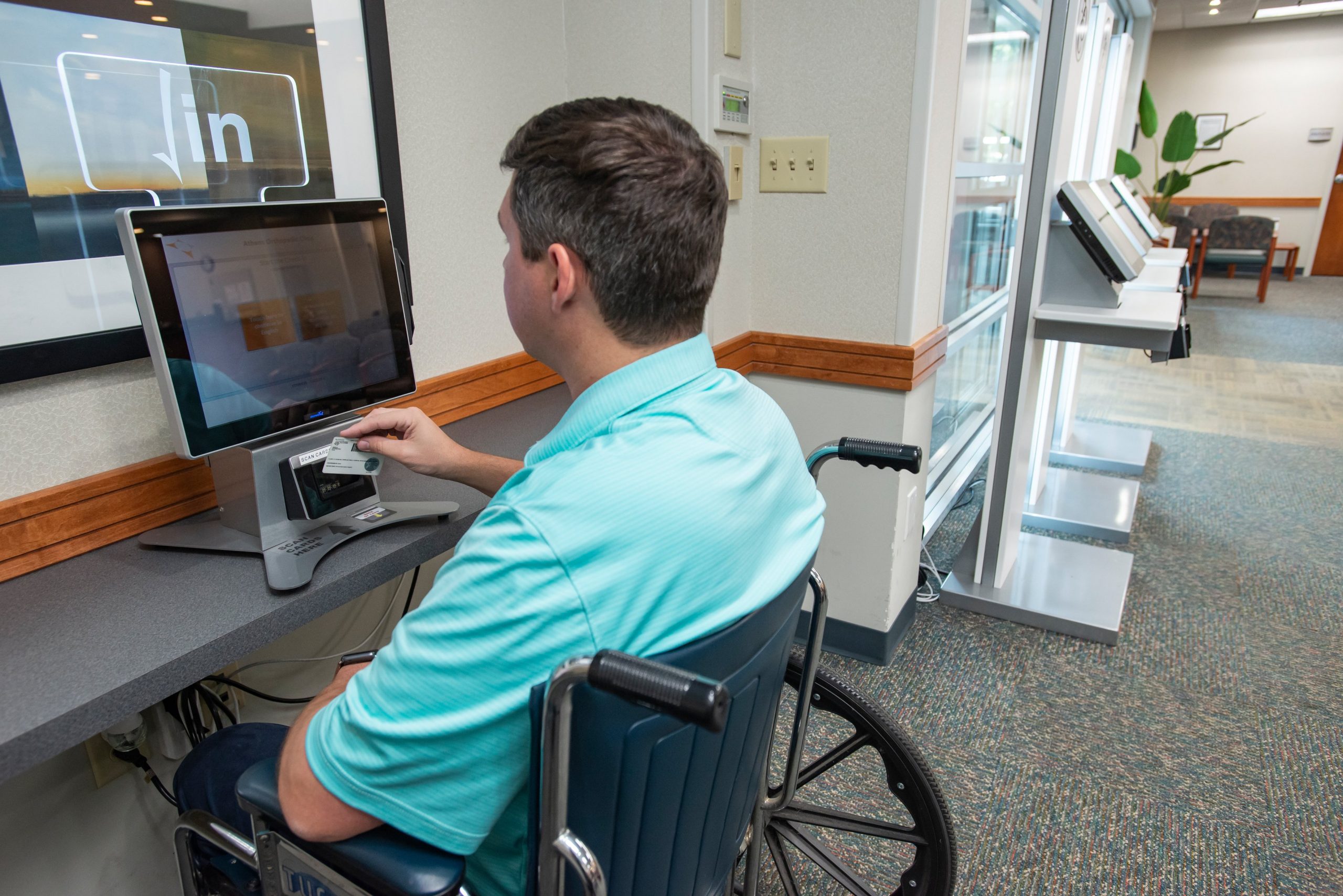 Patient in wheelchair using Clearwave Connect tablet to check in to medical appointment