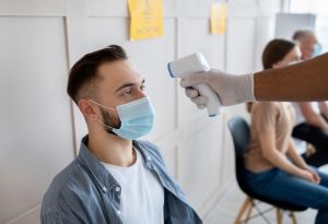 A man with a mask getting his temperature checked