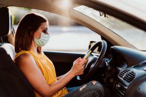 woman sitting in her parked car and using cell phone