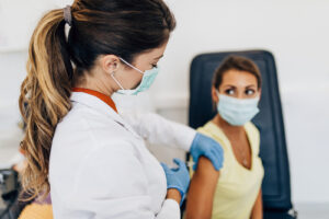 A masked medical worker giving a vaccination